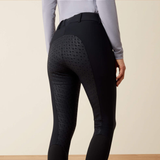 Rear view of a person wearing black equestrian riding breeches with textured patterned side panels and a light gray long-sleeve top, against a plain beige studio background.