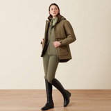 Lady wearing a khaki coloured jacket with a dark green zip against a beige background. 