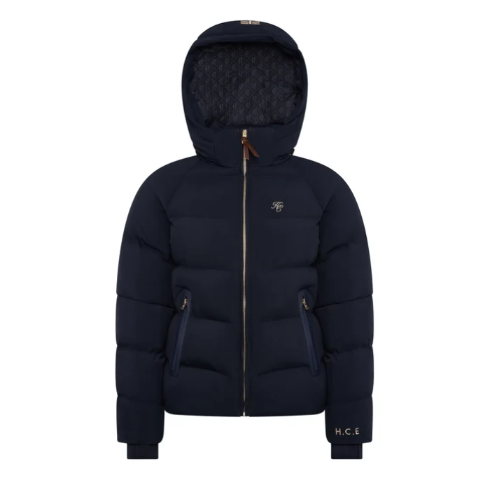 Holland Cooper Chiltern Yard Jacket Variant Ink Navy. A navy blue hooded puffer jacket with a gold-tone front zipper, zippered hand pockets, and a small embroidered logo on the left chest, shown against a plain white background.