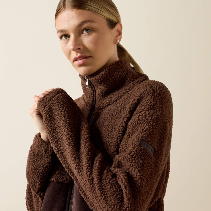 Ariat Ladies Laviolette Full Zip Jacket Variant Chocolate Plum. A woman wearing a brown sherpa fleece quarter-zip pullover jacket, photographed against a plain light beige studio background.
