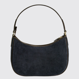 A dark navy blue suede crescent-shaped shoulder bag with gold-tone hardware and a thin dark strap, shown against a light gray background.