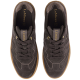 LeMieux AW26 Stockbridge Suede Trainers Variant Colour Cocoa.
A pair of brown suede sneakers with gum soles and gold branding details, shown against a plain white background.