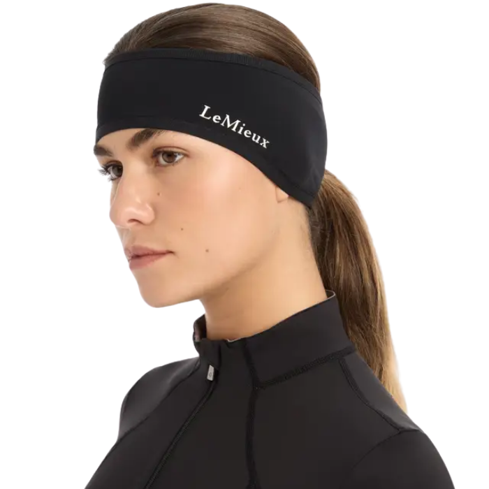 LeMieux AW26 Ear Warmer Headband Variant Colour Black.
A woman in profile wearing a black athletic headband with the brand name 'LeMieux' printed in white on the side, paired with a black athletic top against a plain white background.
