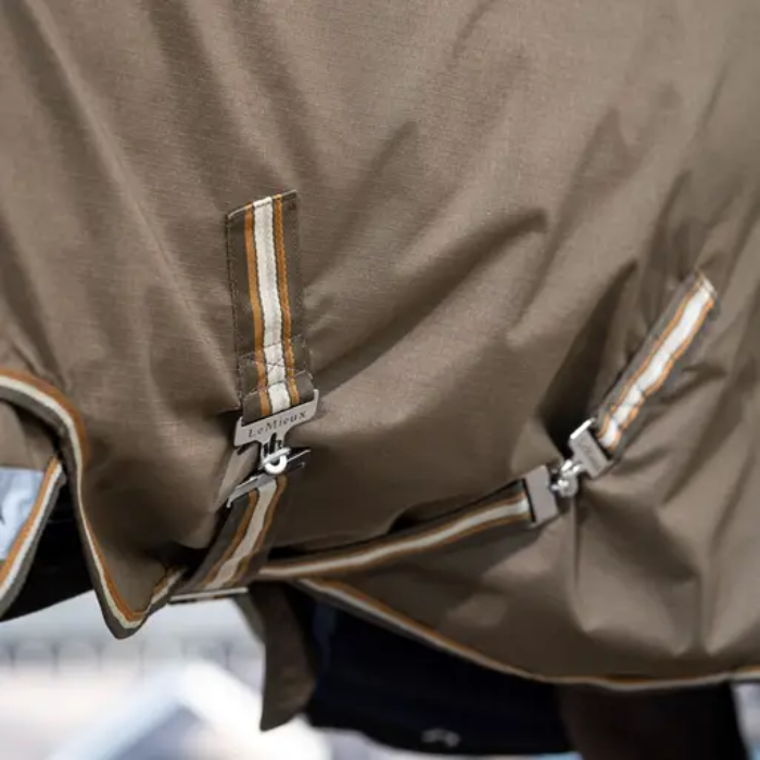 LeMieux AW26 Arika Ripstop 0g Turnout Rug Varient Alpine. Close-up of a brown waterproof rug with adjustable straps and striped trim details.