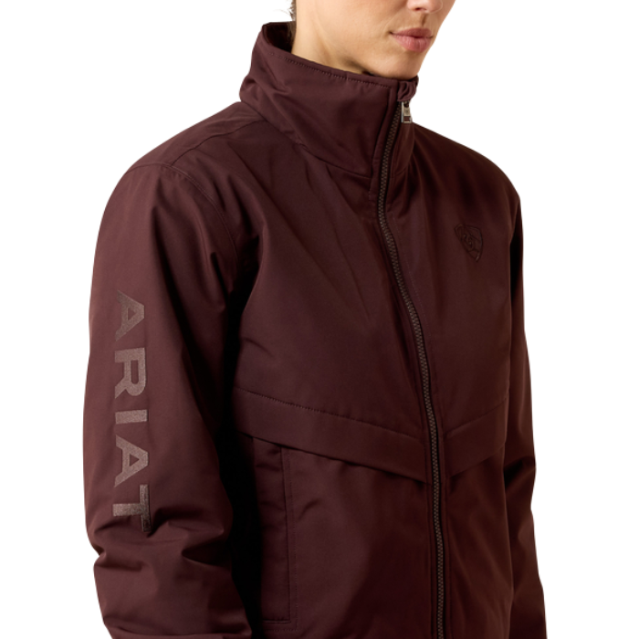 Ariat Women's Stable 2.0 Insulated Jacket Varient Chocolate Plum. Woman wearing a olive bomber coat with a Ariat logo down the sleeve on a white background.