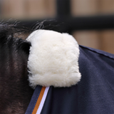 Close-up of a horse's neck with a white fake fur ribbing on a blurred background