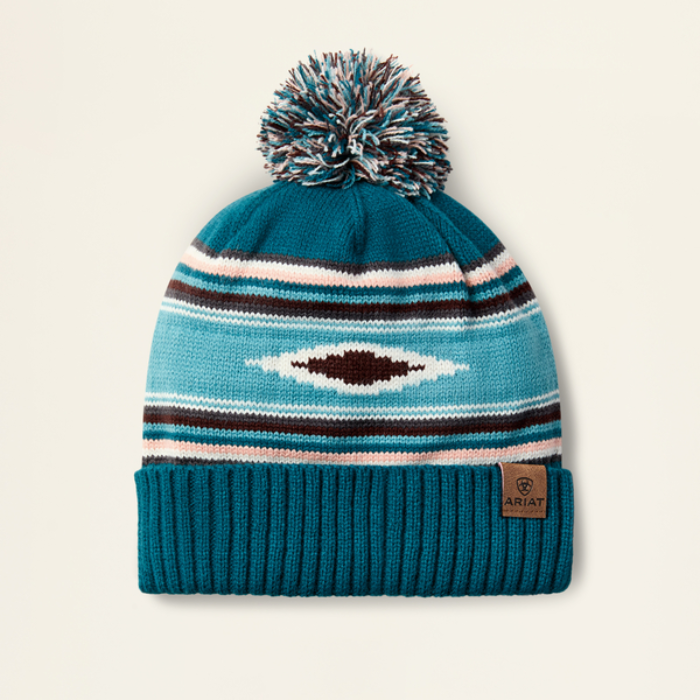 Ariat Ladies Serape Beanie Varient Teal Serape. Teal knit beanie with pattern and pom-pom on a beige background