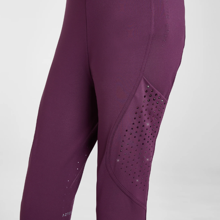 Close-up of a pair of athletic leggings in a deep plum purple color, featuring a textured perforated panel on the side of the leg.