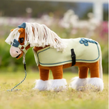 Plush toy horse with a green bridle & rug in a grassy field
