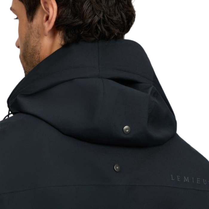 LeMieux AW26 Mens Waterproof Lightweight Jacket Varient Black. Close-up back view of a man wearing a dark navy hooded jacket, showing the hood, snap details, and part of the 'LEMIEUX' logo on the lower back against a white background.