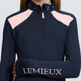 LeMieux AW26 Young Rider Mia Mesh Base Layer Varient Navy. A close-up of a model wearing a navy blue long-sleeve athletic quarter-zip top with light pink shoulder panels and 'LEMIEUX' embroidered in pink on the left sleeve.