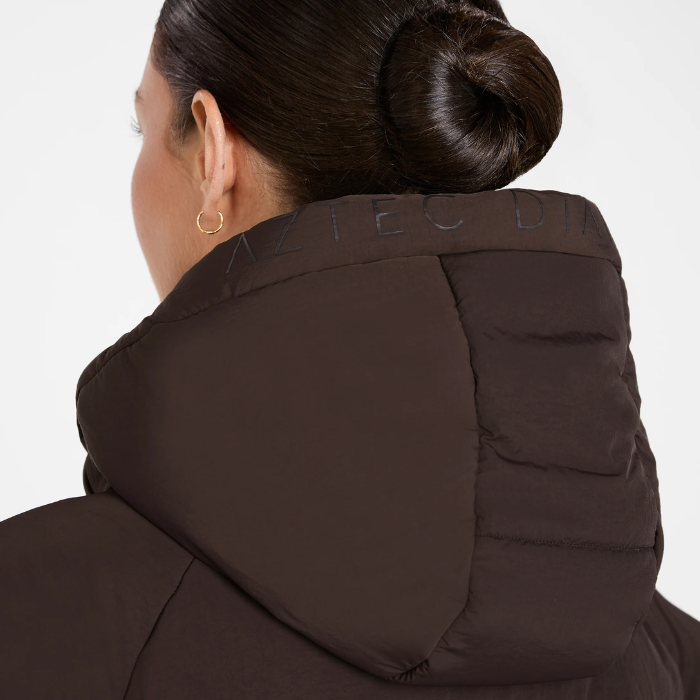 Aztec Diamond Matt Puffer AW26 Variant Espresso. Lady wearing a Brown piffer jacket with large hood and 'AZTEC DIAMOND' branding.