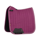 LeMieux AW26 Suede Dressage Square varient Blackberry. A LeMieux quilted horse saddle pad in magenta purple, featuring a black leather girth attachment patch and a black interior lining, set against a plain white background.