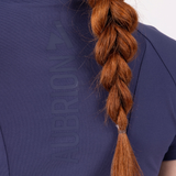Person wearing a blue jacket with a brand logo, featuring a braided red hair.