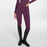 Aztec Diamond AW26 Core Leggings Full Seat Variant Plum. A model wearing high-waisted, form-fitting equestrian breeches in a deep plum purple, paired with black riding boots, shown from the waist down on a light gray studio background.