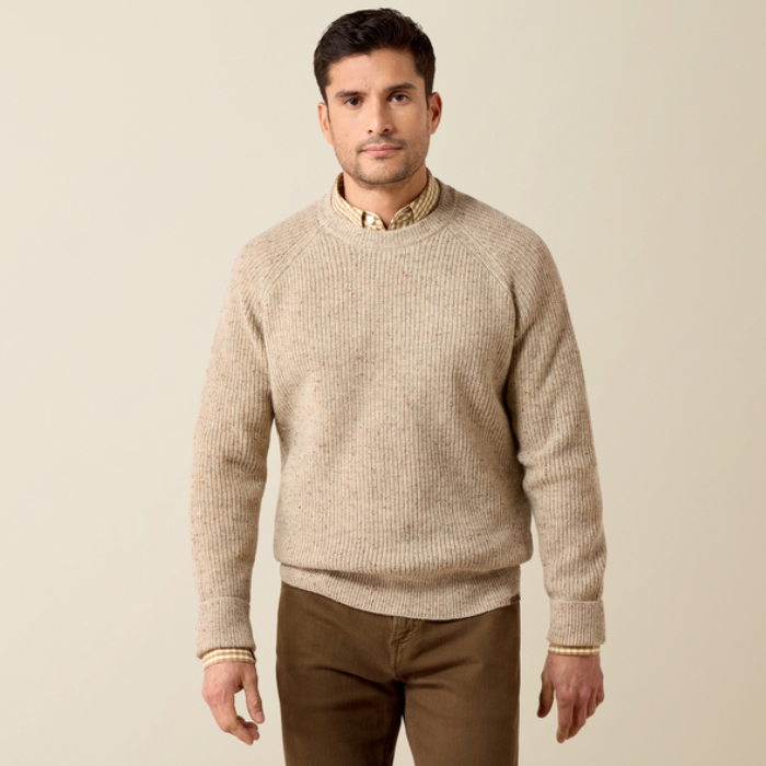 Ariat Men's Heddon Sweater Varient Oatmeal Heather. Man wearing a beige coloured wool jumper and brown trousers on a beige background. 