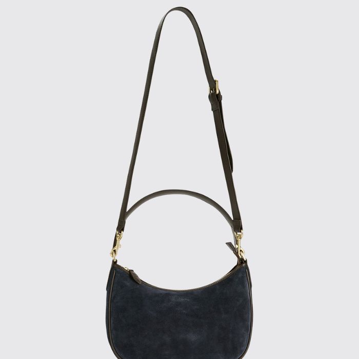 A dark navy blue suede crescent shoulder bag with a matching dark strap and gold-tone hardware, shown against a light gray background.