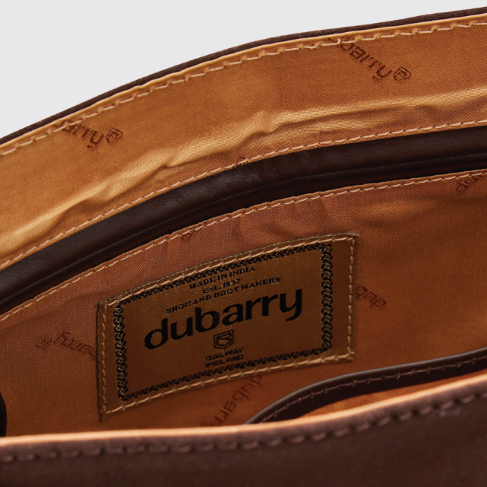 Dubarry Of Ireland Monart Bag Variant Cigar. Close-up of the interior lining of a brown leather bag, showing a stitched brand label that reads dubarry, with tan and dark brown interior panels and visible stitching.