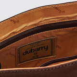 Dubarry Of Ireland Monart Bag Variant Cigar. Close-up of the interior lining of a brown leather bag, showing a stitched brand label that reads dubarry, with tan and dark brown interior panels and visible stitching.