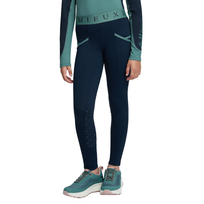 LeMieux AW26 Mini Pull Ons Varient Navy/Aloe. A model wearing dark navy blue athletic leggings with teal long-sleeve top and teal sneakers, shown from the waist down on a white background.
