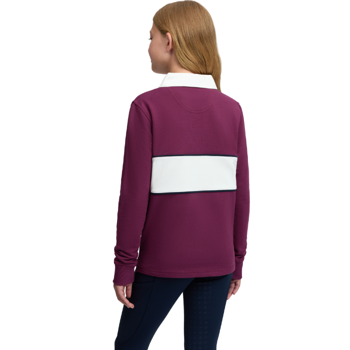 LeMieux AW26 Young Rider Riley Rugby Shirt Varient Blackberry. A woman shown from the back wearing a long-sleeve rugby-style top in deep plum purple with a wide white horizontal stripe across the upper back and a white collar, paired with dark blue jeans against a plain white studio background.
