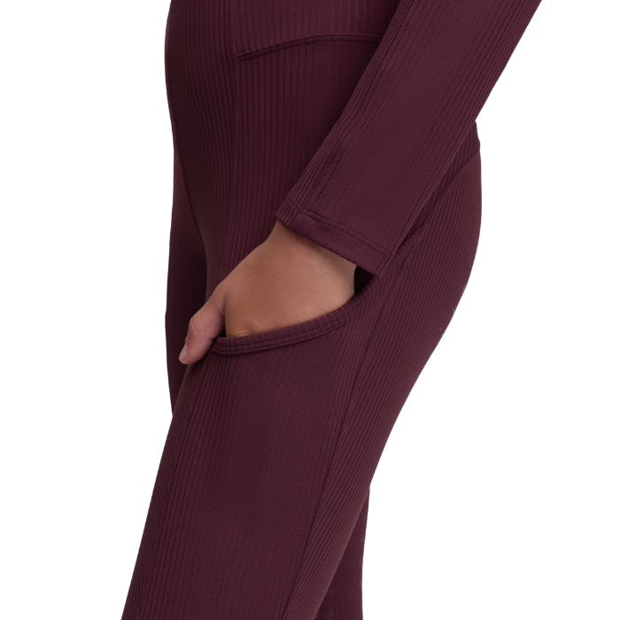 LeMieux AW26 Young Rider Orla Ribbed Pull Ons Varient Bramble. Close-up of a person wearing ribbed burgundy leggings with a side pocket, showing the side profile and hand in the pocket against a white background.