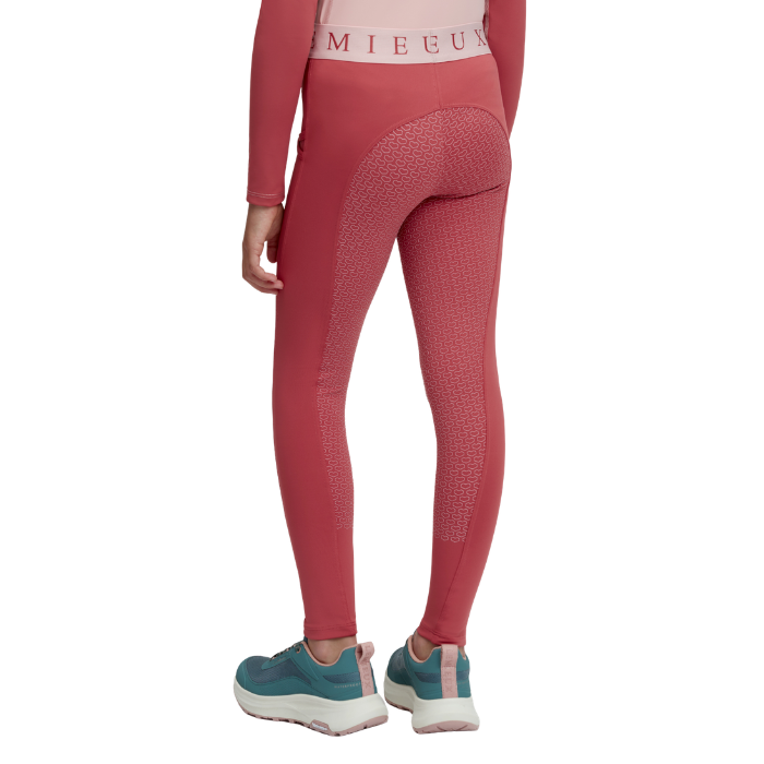 LeMieux AW26 Mini Pull Ons Varient Spiced Earth. A model shown from the back wearing pink textured leggings with a matching waistband, paired with teal sneakers, on a solid white background.