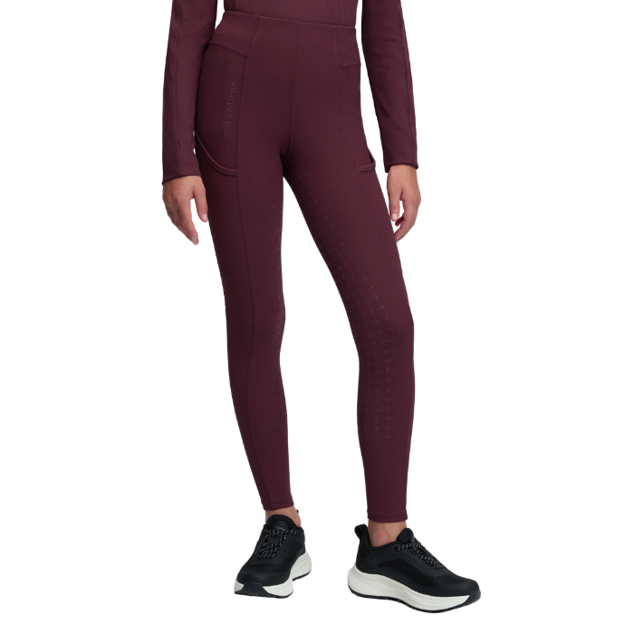 LeMieux AW26 Young Rider Orla Ribbed Pull Ons Varient Bramble. A model wearing high-waisted, long-sleeve athletic leggings in a deep burgundy color, paired with black sneakers, shown against a plain white background.