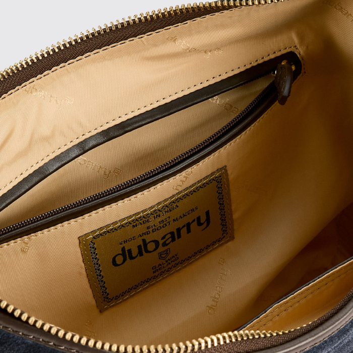 Close-up of the interior of a bag showing a tan nylon lining, a zippered pocket, and a sewn-in brand label reading dubarry.
