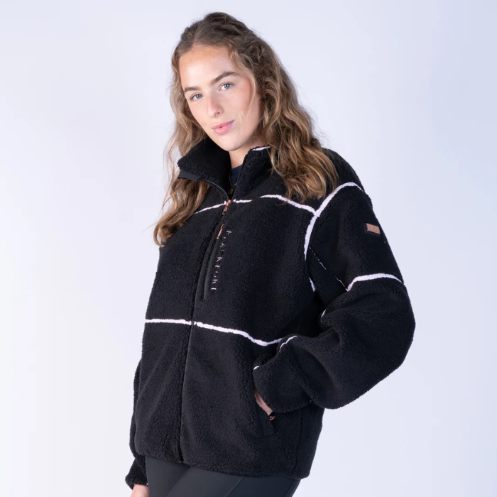 Blackfort AW26 Layla Fleece Variant Black & Blush. A woman wearing a black fleece pullover jacket with white contrast stitching and a half-zip front, photographed against a light gray studio background.