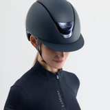 Person wearing a dark gray equestrian helmet with LeMieux branding on a light gray background