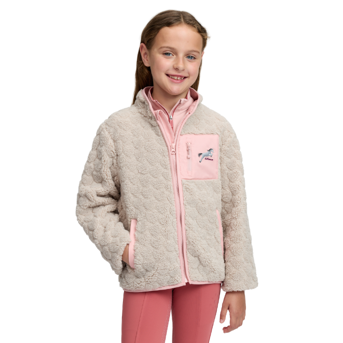 LeMieux AW26 Mini Thora Heart Fleece Varient Stone. A young girl smiling while wearing a light beige sherpa fleece jacket with pink trim and a pink chest pocket featuring a horse graphic, paired with pink leggings, against a plain white background.