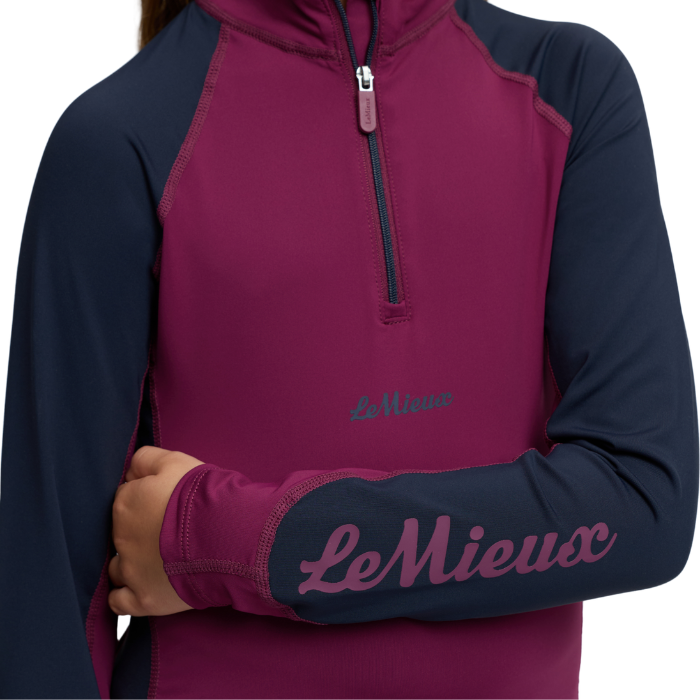 LeMieux AW26 Mini Base Layer Varient Blackberry. A close-up of a long-sleeve quarter-zip pullover from Le Mieux, featuring a deep magenta body and navy sleeves, with the brand name 'Le Mieux' printed in script on the left sleeve.