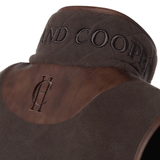 Holland Cooper Country Fleece Gilet Variant Chocolate. Close-up of a brown gilet with embossed leather panels and embroidered branding.