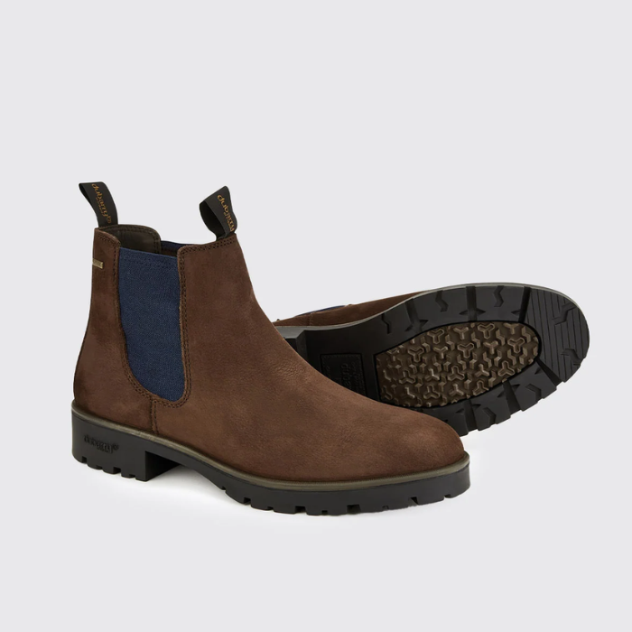 Dubarry Mens Antrim Country Boots Variant Java. A pair of brown suede Chelsea boots with blue elastic side panels, shown on a light gray background. One boot is standing upright, and the other is turned to show the treaded outsole.