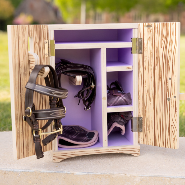 LeMieux AW26 Toy Pony Tack Locker Wooden Varient Brown. Open tack box with purple shelves and saddle stand on  concrete floor.