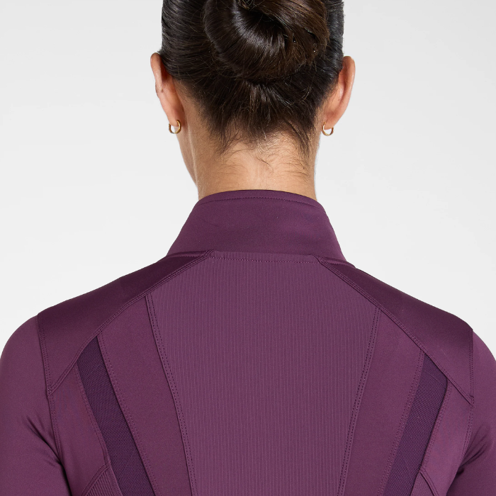 Aztec Diamond AW26 Core Fitted Jacket Variant Plum. Rear view of a woman wearing a purple athletic top with a high collar and textured back panels, shown against a light grey studio background.