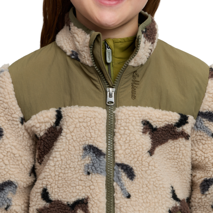 LeMieux AW26 Mini Theo Pony Fleece Varient Willow Green. Close-up of a fleece jacket with a solid olive green upper panel and a lower sherpa section in a beige camouflage pattern with brown, gray, and black shapes. The brand name 'LeMieux' is embroidered on the chest