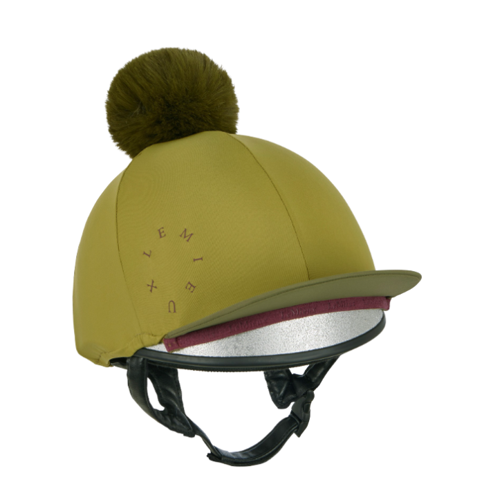 LeMieux AW26 Classique Pom Hat Silk Variant Colour Gooseberry.
An gooseberry green equestrian riding helmet with a matching pom-pom on top, featuring a silver inner visor trim and black chin straps, shown against a plain white background.