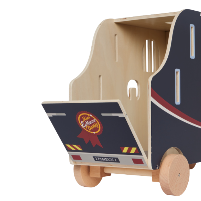 LeMieux AW26 Toy Pony Lorry Wooden Varient Brown. A wooden toy truck with a natural light wood interior and wheels, featuring a navy blue exterior with red and white graphic accents and a ribbon badge on the back panel.