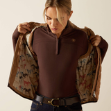 Woman wearing a brown shirt and patterned jacket against a plain background