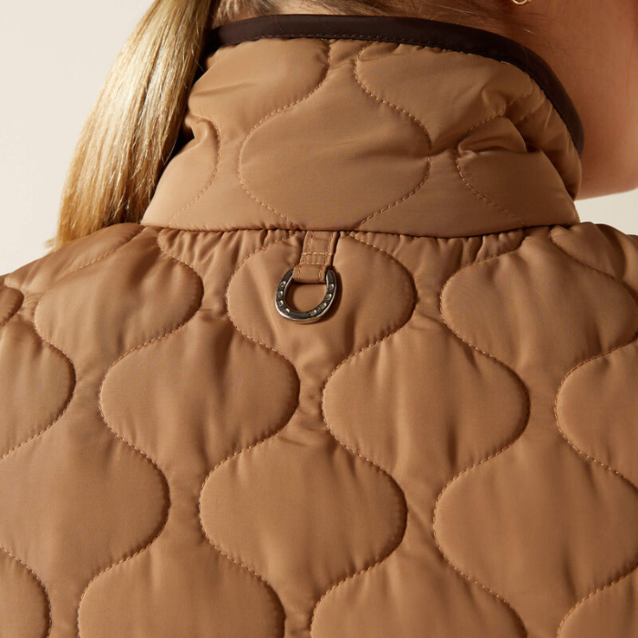 Close-up of a brown quilted jacket with a horse shoe emblem.