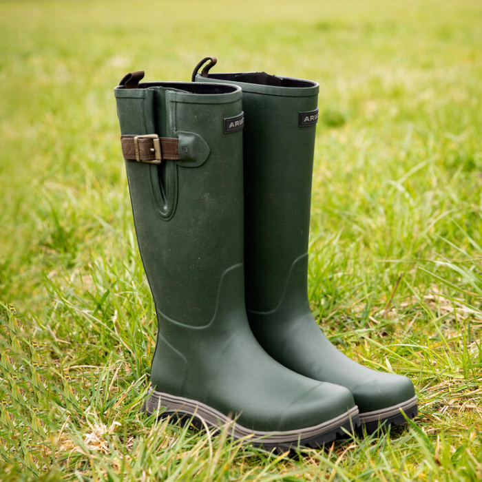 Green rubber boots with a buckle on grass