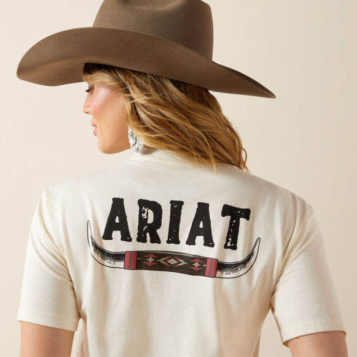Person wearing a light Ariat t-shirt with a brown cowboy hat on a beige background
