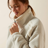 Woman wearing a light-colored fleece jacket with a neutral background