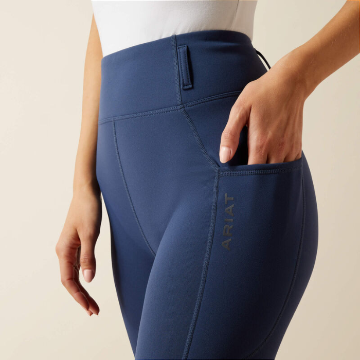 Navy blue riding pants with a visible brand logo on a beige background