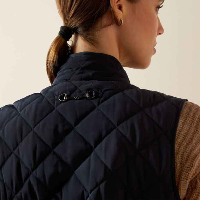 Person wearing a navy quilted gilet with a neutral background