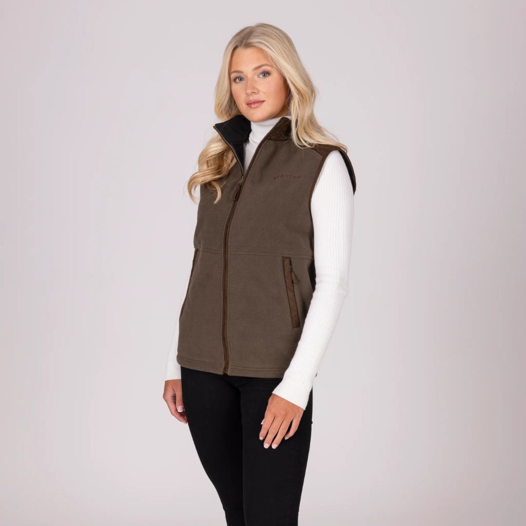 Woman wearing a brown gilet over a white shirt on a light grey background