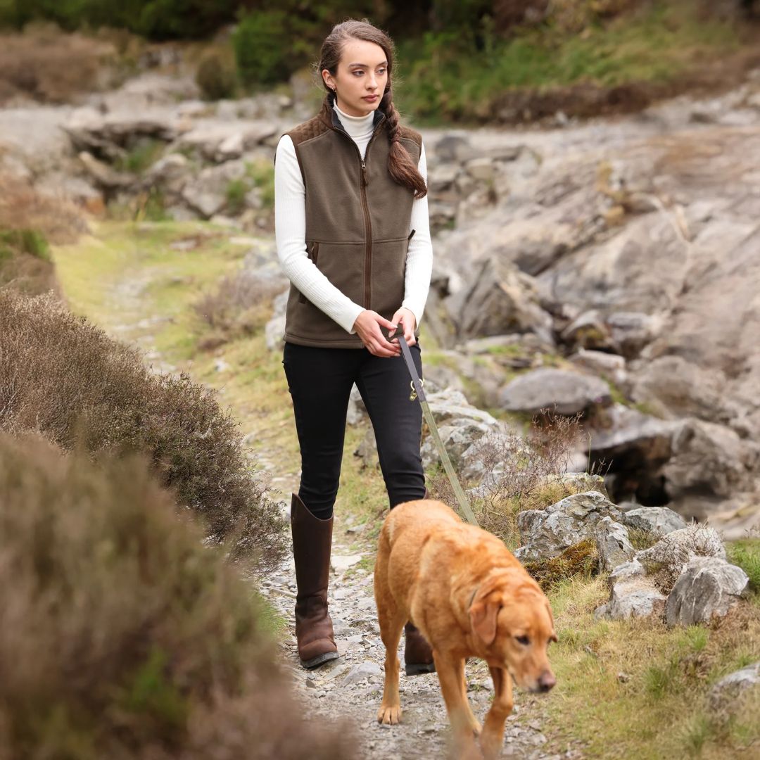 Woman walking a dog on a rocky path in a natural setting