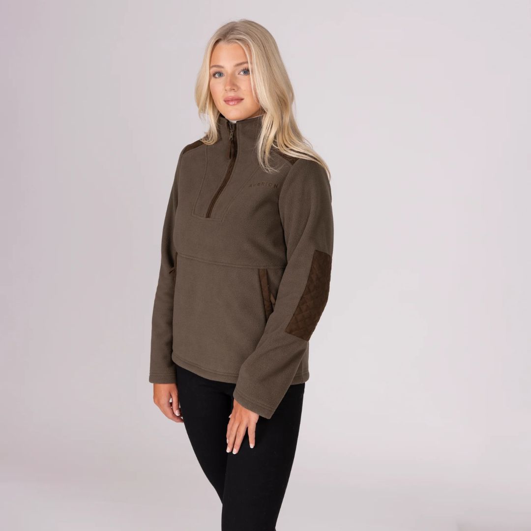 Woman wearing a brown pullover with a high collar on a light grey background